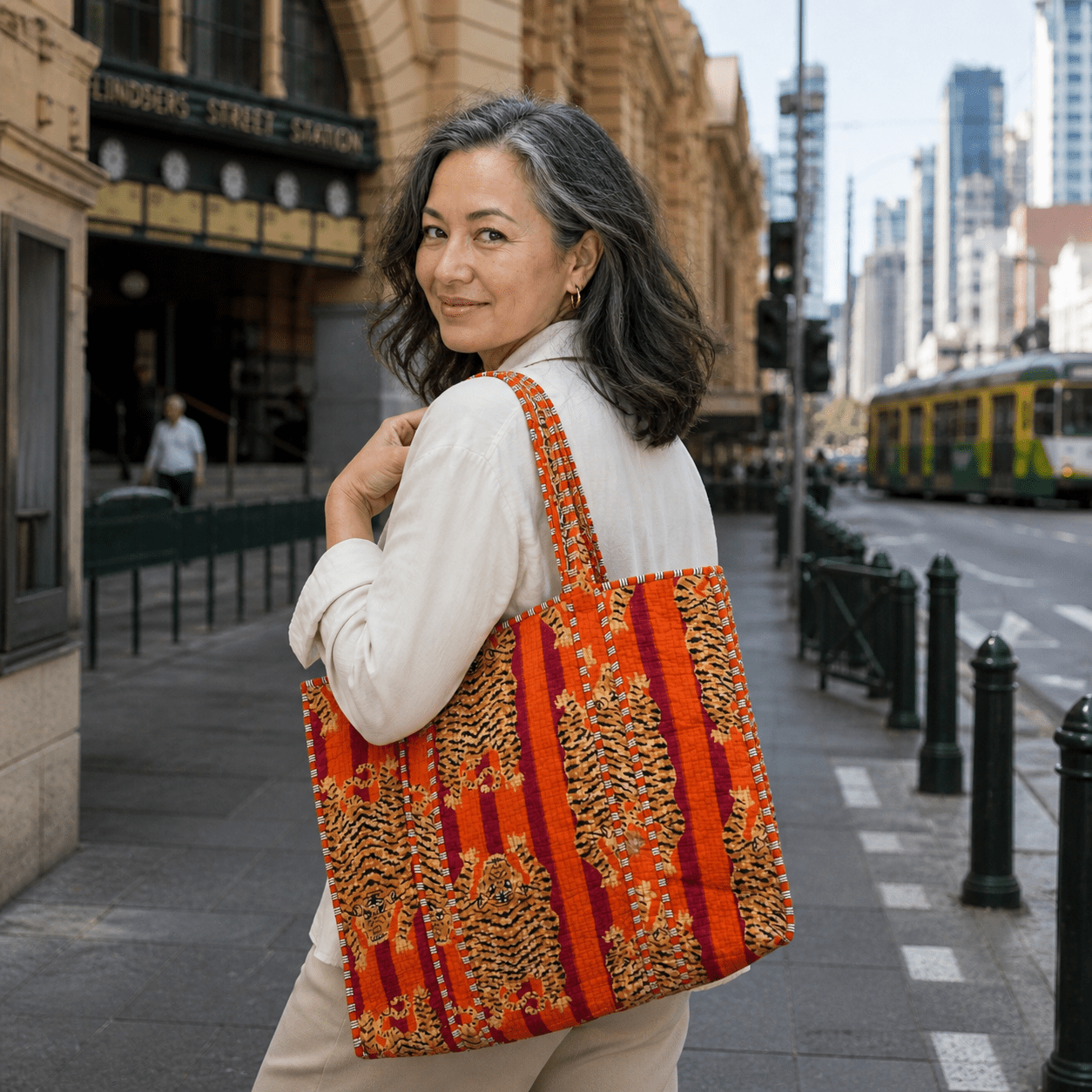 A colorful quilted tote bag with wide handles, featuring bold orange, red, and tan striped patterns with tiger-like prints, shown against a plain light background.